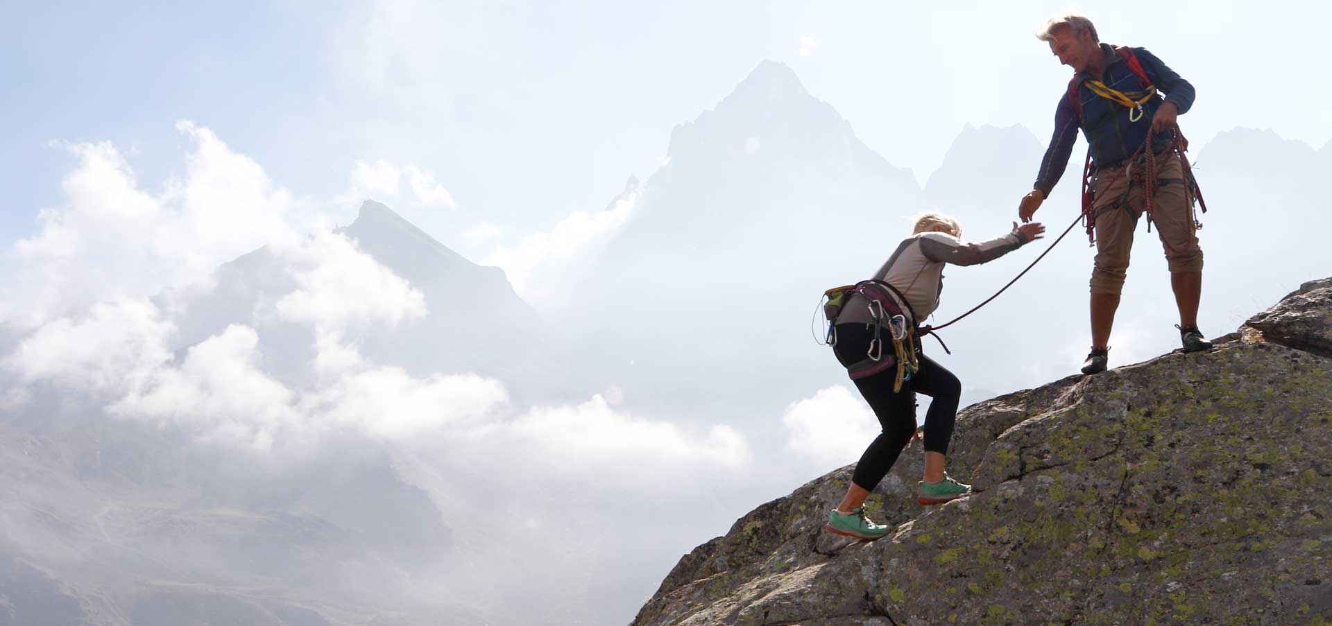 A man and a Women climbing a mountain with ropes.