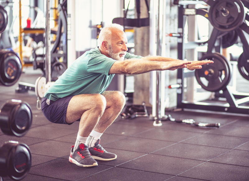 An older man doing a squat